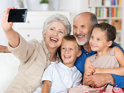 Eine ältere Frau und ein älterer Mann machen ein Selfie mit zwei Kindern, während sie lächeln.
